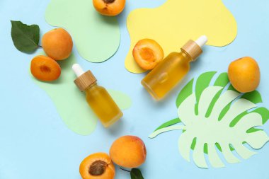 Taze kayısılı kozmetik yağlar ve renkli arka planda kağıttan yapılmış palmiye yaprakları.