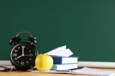 Elma, çalar saat, kitaplar ve karatahtanın yanındaki masada kağıt uçak. Okul konseptine dönelim.