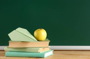 Elma, kağıt uçak ve masadaki karatahtanın yanında kitaplar. Okul konseptine dönelim.