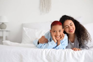 Küçük Afro-Amerikalı çocuk, annesi yatak odasında yatıyor.