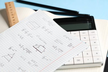 El yazısıyla yazılmış matematik formülleri ve mavi arkaplanda kırtasiye defteri