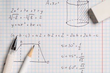 El yazısıyla yazılmış matematik formülleri ve arkaplan olarak kırtasiye defterleri, yakın plan