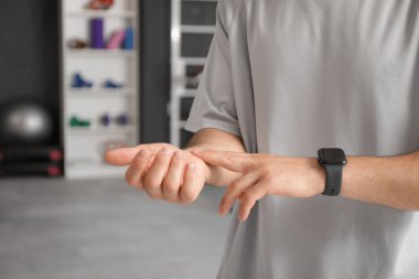 Sportif genç adam spor salonunda nabzını kontrol ediyor, yakın plan.