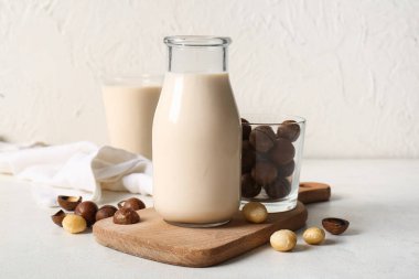 Beyaz arka planda bir şişe ve bir bardak taze Macadamia sütü.