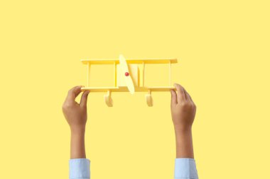 Sarı arka planda oyuncak uçağı olan çocuk