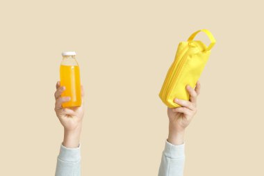 Bej arka planda meyve suyu ve kalem kutusu olan çocuk