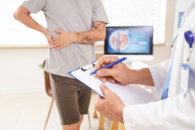 Mature urologist writing on clipboard in clinic, closeup clipart