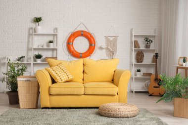 Konforlu kanepe, raflar ve oturma odasındaki beyaz tuğla duvarda can simidi halkası.