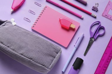 Leylak arka planında farklı kırtasiye malzemesi olan gri kalem kutusu. Üst görünüm