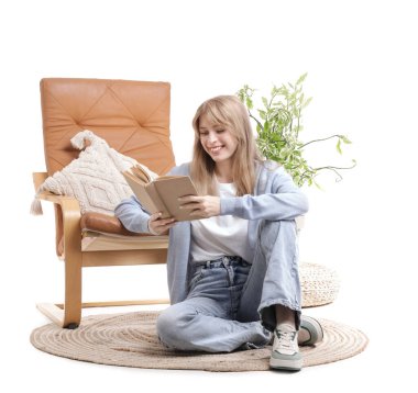 Kitap okuyan genç bir kadın, beyaz arka planda izole bir şekilde, koltuğun yanında oturuyor.