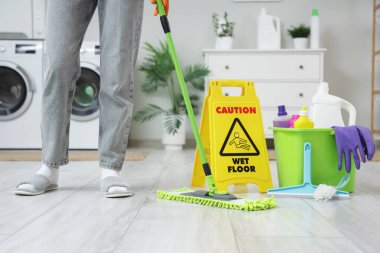 Çamaşır odasında yerleri paspaslayan hademe, yakın çekim.