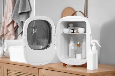 Tuvaletteki dolapta kozmetik ürünleri olan küçük bir buzdolabı.