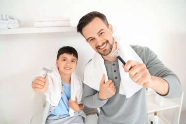 Mutlu baba ve küçük oğlu banyoda havluyla jilet tutuyorlar.