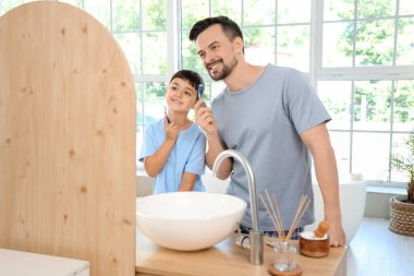 Mutlu baba ve küçük oğlu banyoda aynanın yanında tıraş bıçaklarıyla