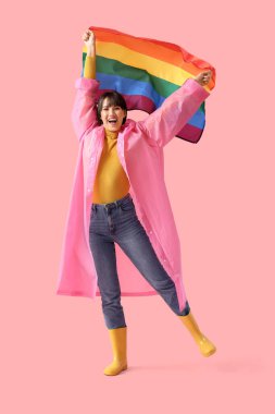 Pembe arka planda LGBT bayrağı olan mutlu genç bir kadın.