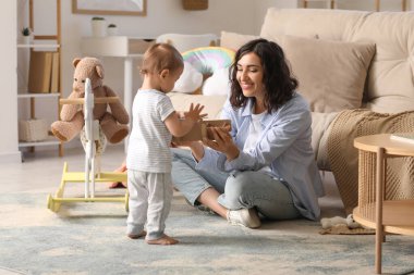 Güzel, genç, mutlu bir anne, küçük şirin bir bebek ve evde oturan ahşap bir uçak.