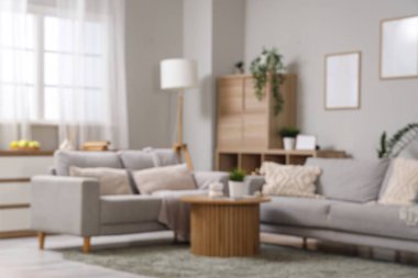 Gri kanepeleri, ahşap kahve masası ve çiçekleri olan şık oturma odasının bulanık görüntüsü