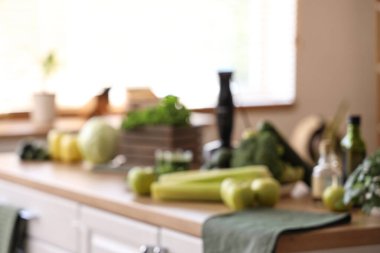 Mutfaktaki masada farklı taze sebzeler ve meyvelerle sağlıklı yeşil smoothie karışımı, bulanık görünüm.