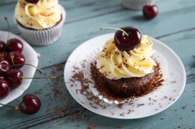 Tatlı vişneli kek ve mavi ahşap arka planda böğürtlenli tabak.