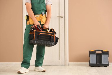 Evinin yakınında alet çantalı bir erkek işçi.