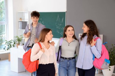 Sınıfta sırt çantalı bir grup genç öğrenci.