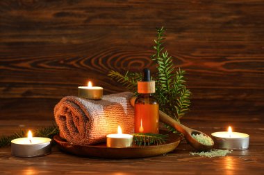 Spa aksesuarları, gerekli yağ şişesi ve ahşap masa üzerinde köknar dalları olan kompozisyon