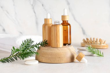 Temel yağ şişeleri, spa taşları ve hafif arkaplanda köknar dalları olan bileşim