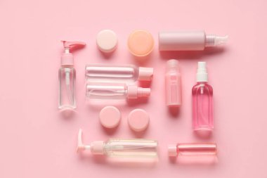 Pembe arka planda farklı seyahat kozmetik ürünleri içeren kompozisyon