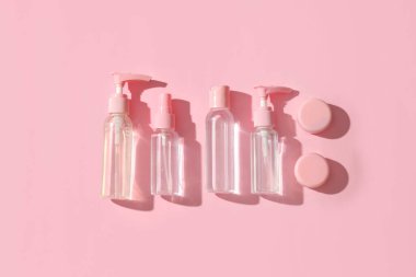 Pembe arka planda farklı seyahat kozmetik ürünleri.