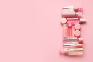 Pembe arka planda farklı seyahat kozmetik ürünleri içeren kompozisyon