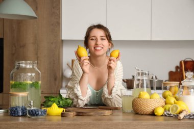 Mutfaktaki masada limonlu ve limonlu genç bir kadın.