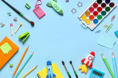 Çerçeve, mavi arka planda farklı kırtasiye malzemeleri ve plastik roketlerden yapılmış. Üst görünüm