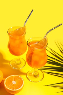 Sarı arka planda Aperol spreyli kokteyl ve palmiye yaprağı.