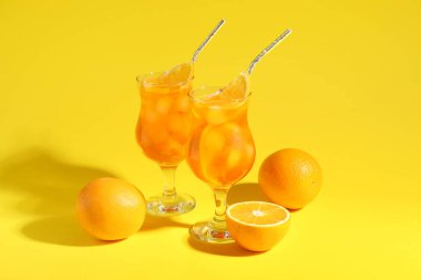 Sarı arka planda Aperol sprey kokteyli ve portakallar.