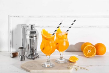 Portakallı ve beyaz ahşap masada sallanan Aperol spreyli kokteyller.