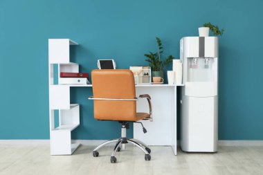 Ofiste mavi duvarın yanında kağıt bardak ve su soğutuculu modern işyeri