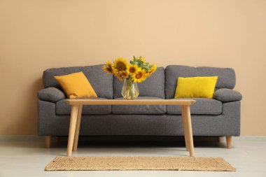 Oturma odasında ayçiçekleri olan rahat bir kanepe ve kahve masası.