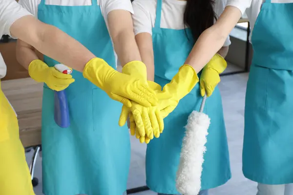 stock image Group of young janitors putting hands together in office, closeup