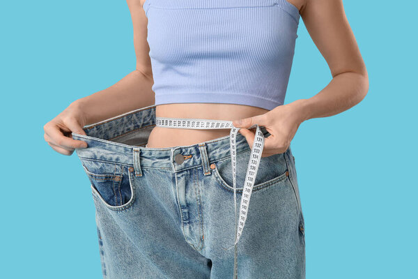 Молодая женщина в джинсах на синем фоне. Концепция питания