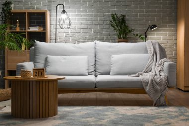 Oturma odasının içindeki tuğla duvarın yanındaki gri kanepe.