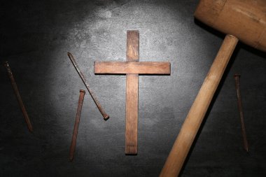 Wooden cross with nails and mallet on dark background. Good Friday concept