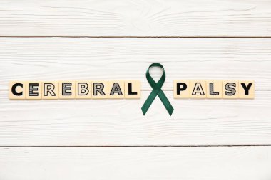 Saten yeşil kurdele ve tahta zemin üzerinde CEREBRAL PALSY yazılı plastik harfler