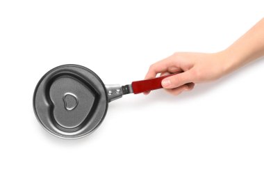 Beyaz arka planda kalp şeklinde bir tavayı tutan kadın.