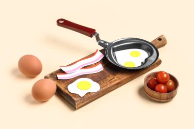 Kağıt yumurta, pastırma ve bej arka planda malzemeyle kalp şeklinde kızartma tavası.