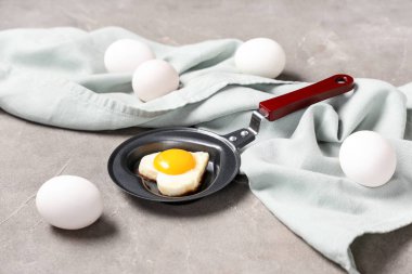 Kızartma tavasında kalp şeklinde sahanda yumurta, yumurta ve arkaplanda peçete kompozisyonu