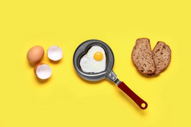 Yumurta kabuğu, bir parça ekmek ve sarı arka planda kalp şeklinde kızarmış yumurta.