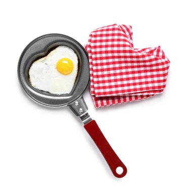 Kalp şeklinde sahanda yumurta ve beyaz arka planda peçete ile kızartma tavası