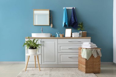 Modern banyodaki hasır çamaşır sepetine bir yığın temiz yumuşak havlu.