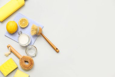 Farklı temizlik malzemelerine sahip kompozisyon kabartma tozu ve gri arka planda limonlar.