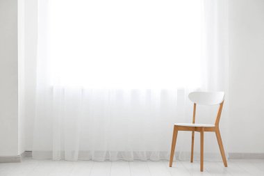 Odada ışık perdesinin yanındaki sandalye.